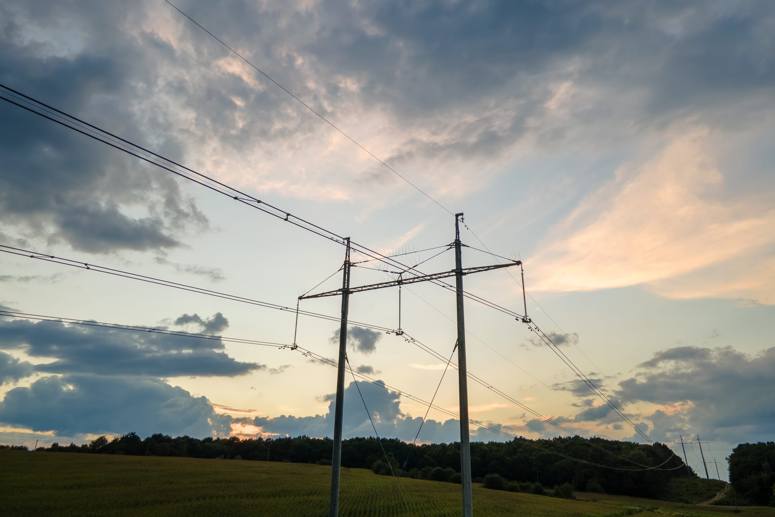 High voltage tower with electric power lines at sunset.
